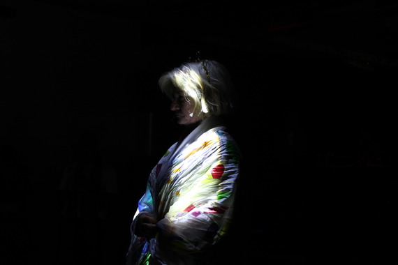 Slightly haunting dimly lit person in white garments in pitch black room.