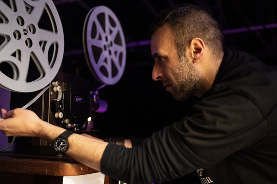 Close up of a bearded person working with an old-school film projector.