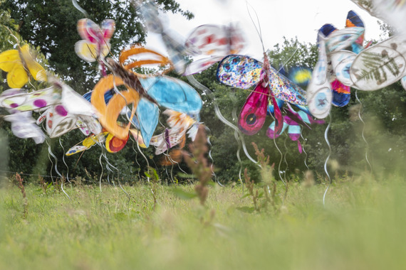 Psychedelic butterfly sculpture display in the green gardens of a stately home.