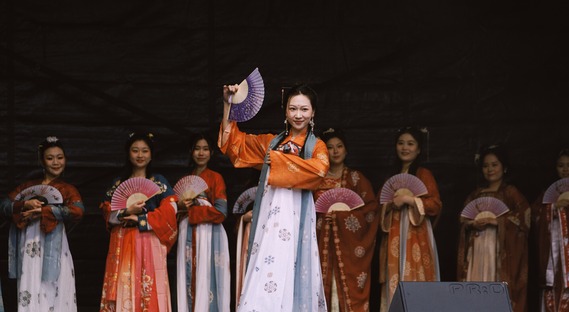 Group of people in oriental dress on stage for Lunar New Year celebrations.