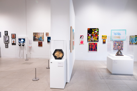A clean, white gallery with colourful artworks on the wall.