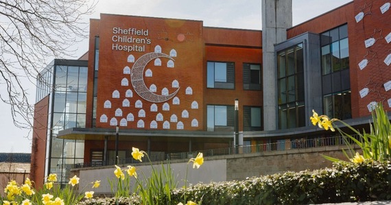 Moon and star shaped lights hang on the side of the Sheffield Children's Hospital, with fresh daffodils in the foreground.