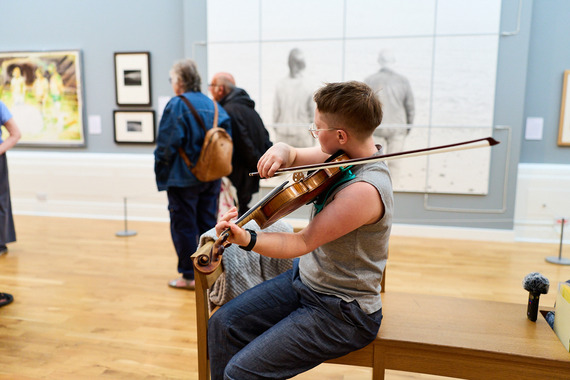 Person playing a violin in an art gallery.