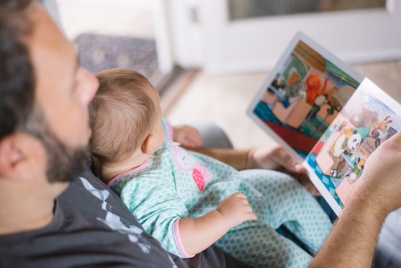 An adult reading a picture book with a baby