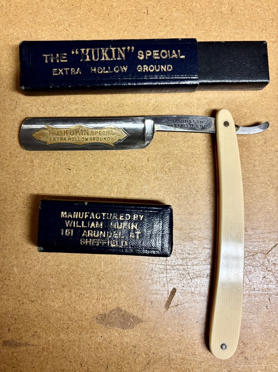 A close up of a shiny straight razor with some words etched into it.