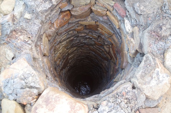The shaft of a well with water at the bottom