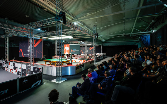 A crowd watches multiple snooker tables during World Championship qualifying in Sheffield.