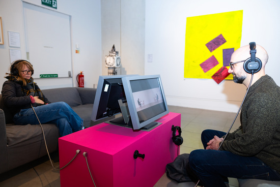 Two people sat with headphones enjoying an art installation.