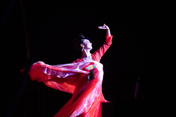 Person in oriental dress elegantly dancing on a dark stage.