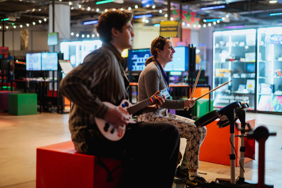 Two people playing a guitar game at an arcade.