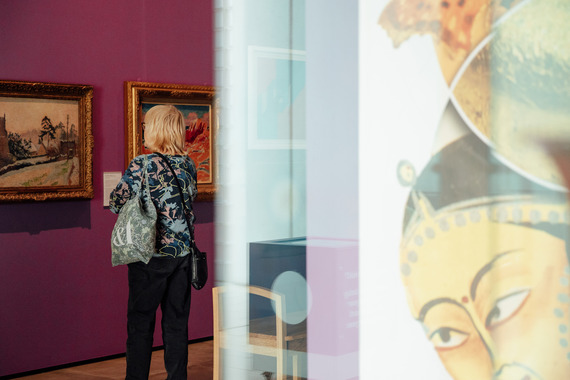 A person browsing vibrant gallery paintings.