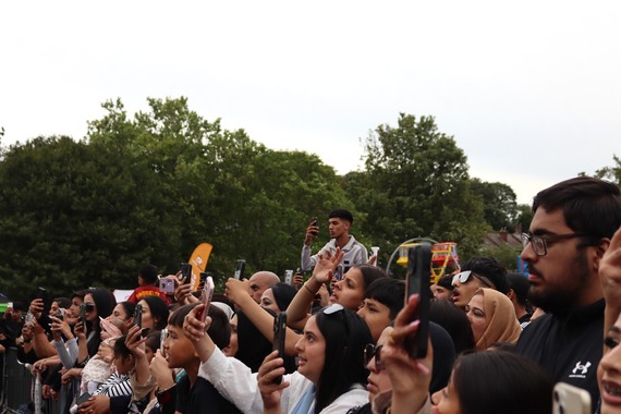 A crowd of people up against a barrier at a festival having a great time.