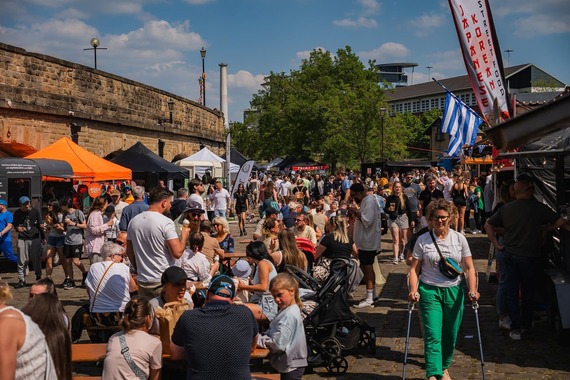 A busy crowd of people in between stalls at Quayside Market on a sunny day