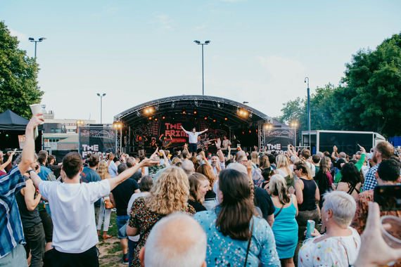 Performers on stage at The Fringe at Tramlines. A crowd can be seen watching on Devonshire Green.