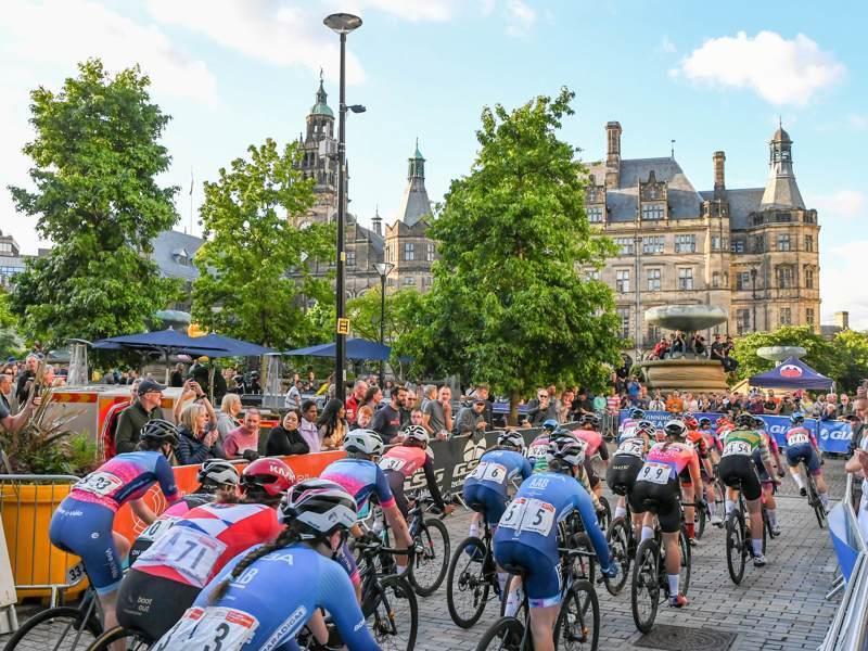 Cyclists race past the Peace Gardens, with the Town Hall in the background.