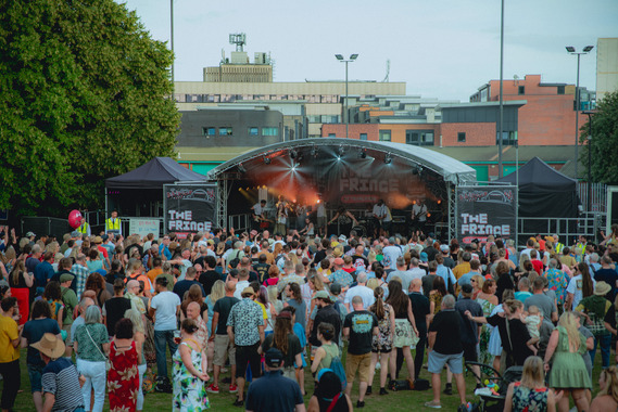 A band performs on stage at The Fringe at Tramlines. A crowd watches on at Devonshire Green.