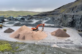 A view of the scord quarry, a large machine sits in the centre surrounded by piles of crushed rock. 