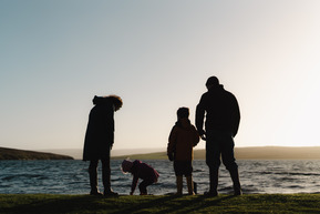 A family silhouetted on a shetland beach