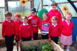Children from Cullivoe School stand around a bed in their polycrub, looking proud