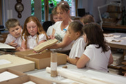 a woman with a group of school children looking at an archive object