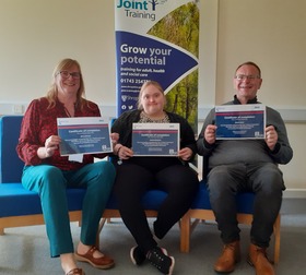 Photograph of Mary, Jessica and Stuart holding their Oliver McGowan trainer certificates and smiling