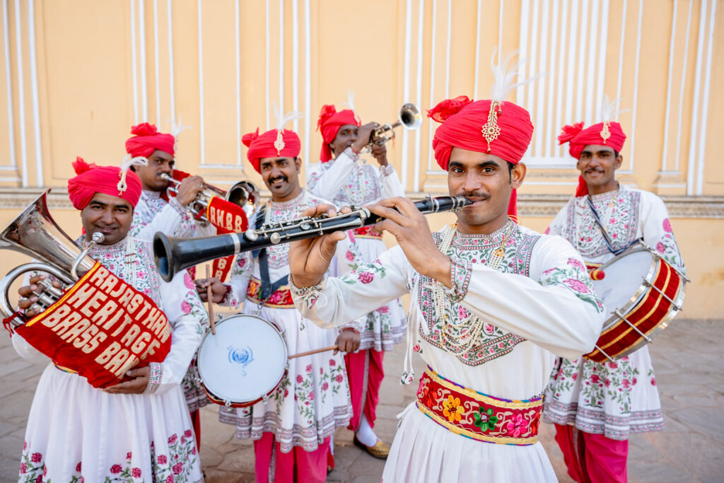 members of a brass band pose with instruments and in traditional indian costume