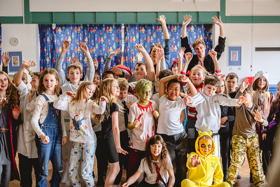 A group of children cheer with their hands in the air 