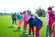 Children outside playing jumping over a rope ladder