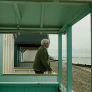 man standing outside beach hut