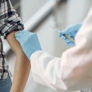 Person receiving vaccination from Doctor in labcoat and gloves