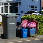 Recycling and waste bags, bins and boxes outside a house ready for collection.
