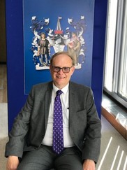 Cllr Stephen George, leader of the council sitting in a chair with the Southend coat of arms behind him.