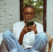 Person sitting on a chair typing on a mobile phone.