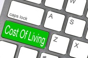 Laptop keyboard with a green button that says "cost of living".