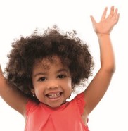 Little girl aged around 3 with her hands in the air and smiling happily