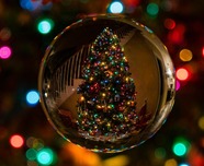 Christmas tree with multicoloured light reflected in a clear bauble.