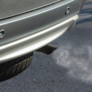 A silver cars exhaust emitting a cloud of fumes.