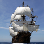 A large wooden Spanish Galleon ship sailing over calm waters on a bright, clear and sunny day.