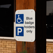 A blue badge sign attached to a wooden beam. It states, blue badge holders only.