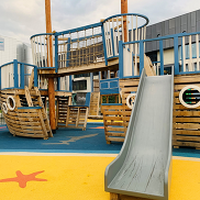 A wooden climbing frame resembling a pirate ship. It has a slide, ladders and climbing nets.