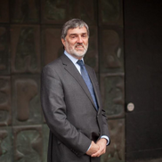 Rob Tinlin posing for a photograph outside of the Civic Centre. He is wearing a dark grey suit jacket with a blue tie and white shirt.