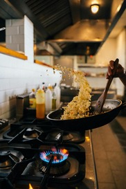 Fried rice cooking in a frying pan over a gas hob in a kitchen