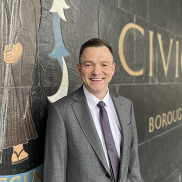 Chief executive Colin Ansell outside of the Civic Centre. He is smiling at the camera, wearing a grey suit jacket and tie with a light shirt.