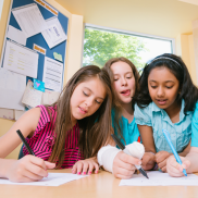 Three school age girls working together at a table.