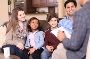 A family of 2 adults and 2 children sitting on a sofa and listening attentively to a professional.