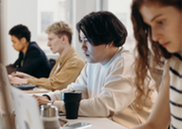 A group of four young people working in a row of computers.