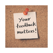 A soft cream paper note on a cork board. The note says "your feedback matters".