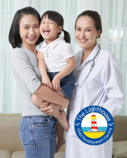 A mother carrying her daughter in arms. Next to them is a nurse wearing a white lab coat.