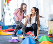 A girl walking on stepping stones, she is being helped by a therapist.
