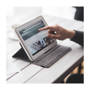 A close of a hand and an index finger touching a tablet.
